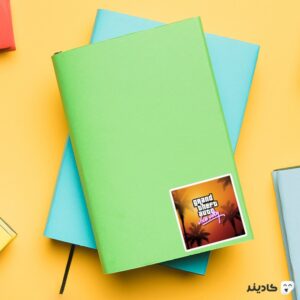 استیکر لپ تاپ جی تی ای - پوستر نارنجی بازی روی دفترچه