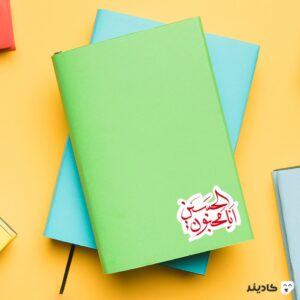 استیکر لپ تاپ امام حسین - من عاشق حسینم روی دفترچه