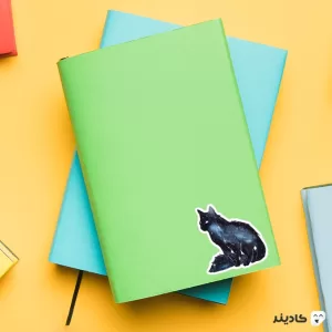 استیکر لپ تاپ استیکر لپ تاپ کول طوری - گربه مشکی پوش روی دفترچه